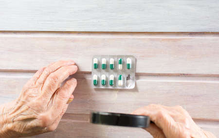 Senior woman inspecting pills with magnifying glassの写真素材