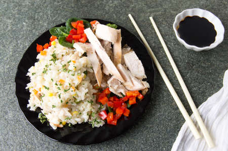 Chicken with rice and vegetables served on a plateの写真素材