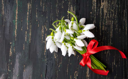Snowdrops bouquet on a dark wooden tableの写真素材
