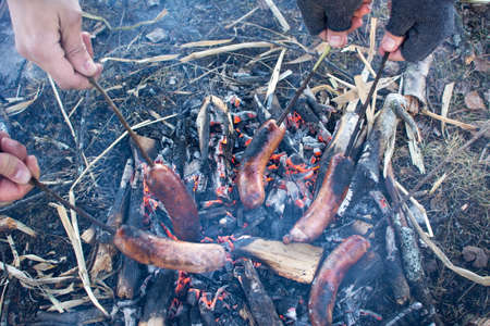 People roasting sausages on top of campfireの写真素材
