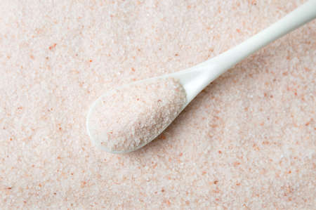 Himalayan salt in a white ceramic spoonの写真素材