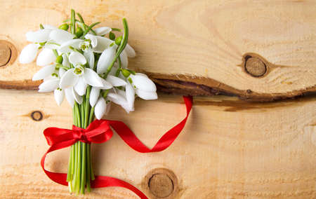 Snowdrops bouquet on a natural wooden boardの写真素材
