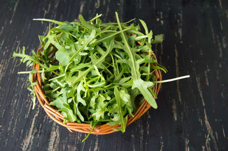 Rucola plant known as  rocket salad in a wicker bowlの写真素材