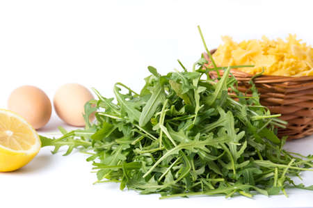Rucola plant green leaves and pasta ingredients on whiteの写真素材