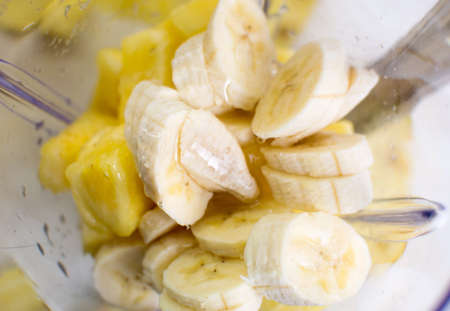 Sliced pineapple and banana in a blenderの写真素材