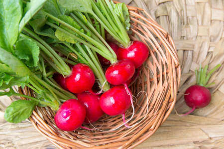 Bunch of radishes with leaves on a wicker tableの写真素材