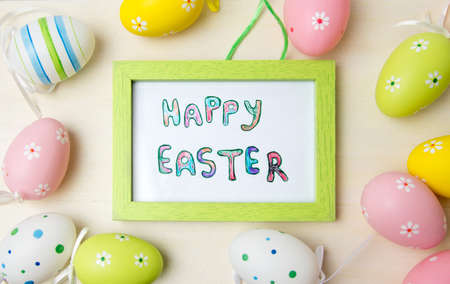 Happy Easter card in a wooden frame with colorful eggsの写真素材