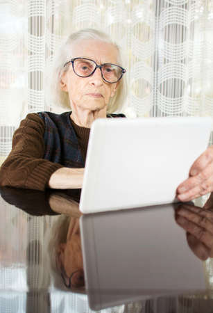 Senior woman using tablet device at homeの写真素材