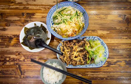 Chinese meal of noodles, kelp soup and sliced pork fried with vegetablesの写真素材