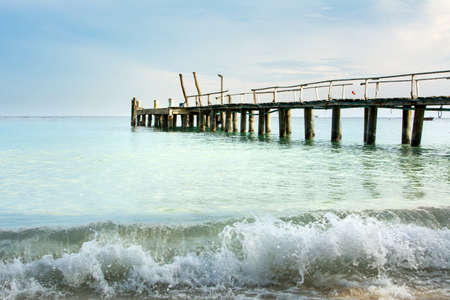 Wooden dock and small wave in Thailand seaside at sunsetの写真素材
