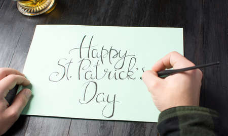 Male writing a Happy St Patrick day calligraphy cardの写真素材