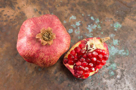 ripe and cut pomegranates on a rustic backrgoundの写真素材