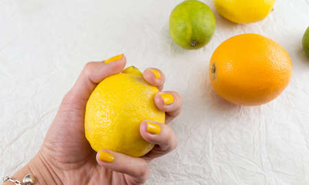 Female hand holding lemon on the tableの写真素材