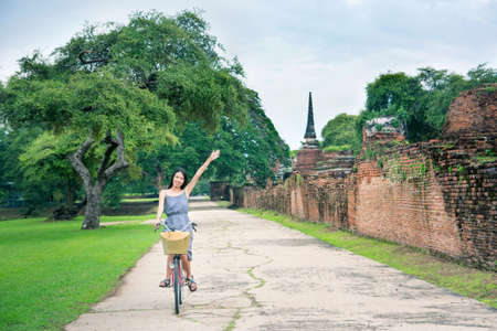 Girl visiting Ayutthaya park in Thailand on bicycleの写真素材