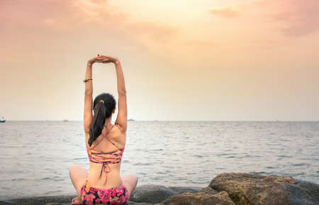 Girl doing yoga exercises at the beach
