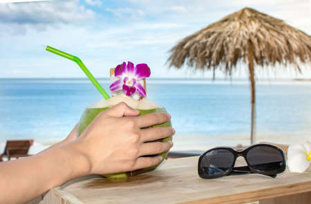 Girl holding fresh coconut at the tropical beach resort