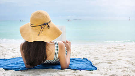Girl reading a book on the sandy beachの写真素材