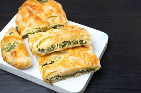 Spinach and cheese pie slices on a wooden tray