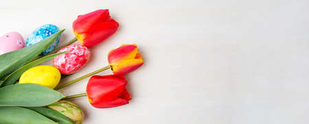 Red tulips and painted Easter eggs on wooden tableの写真素材