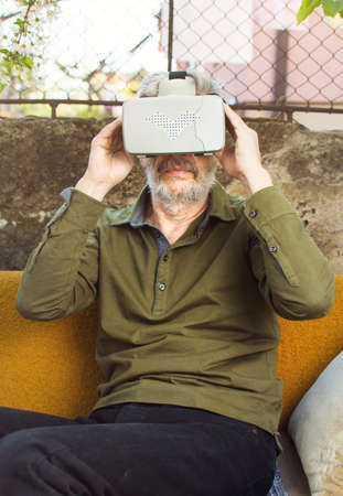 Senior man using virtual reality goggles in the backyard