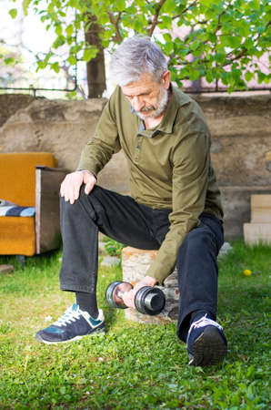 Senior man working out with dumbbell outdoors