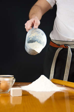 Man pouring flour from the measure bowl on the table