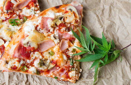 Happy pizza slices with marijuana leaves on paperの写真素材
