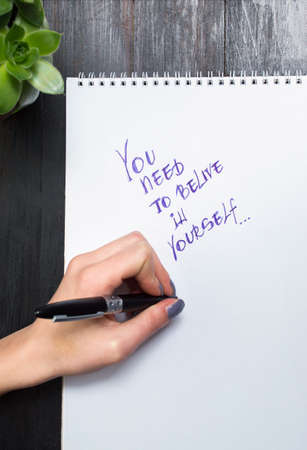 Female hands writing motivational message in a notebookの写真素材