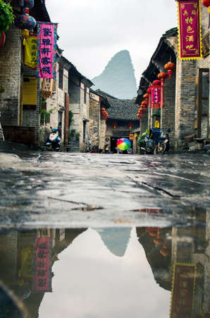 HUZHOU, CHINA - MAY 3, 2017: Huang Yao Ancient Town street in Zhaoping county, Guangxi province. Karst formation reflected in the rain waterのeditorial素材