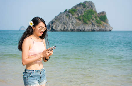 Girl looking at smart phone while walking on the beachの写真素材