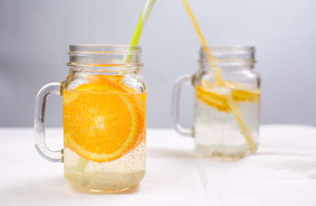 Water with orange and lemon in glass jars. Cold summer drinkの写真素材
