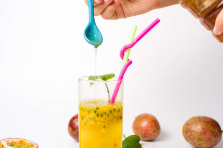 Female hand adding honey in passion fruit juiceの写真素材
