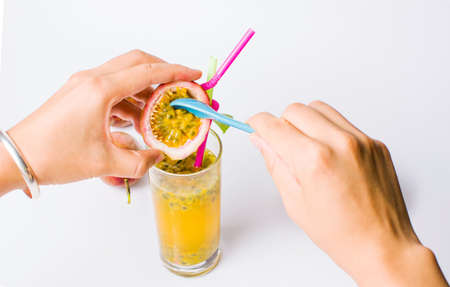 Female hands adding berries into passion fruit juice