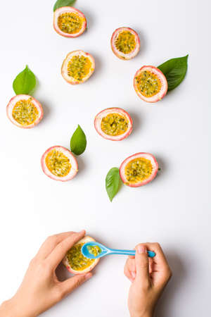 Female eating Passion fruit with a blue spoon on whiteの写真素材