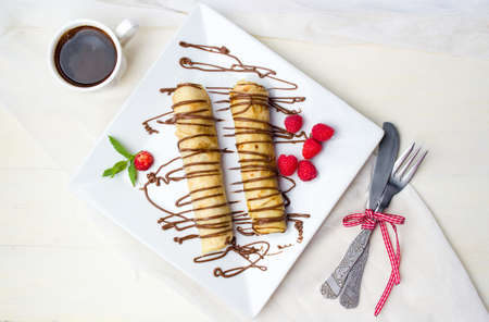 Pancakes with strawberry and chocolate on a white plateの写真素材