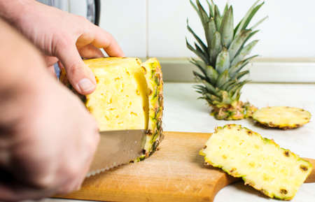 Male hands peeling fresh pineapple skin close upの写真素材