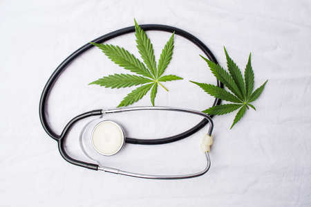 Medical marijuana plant and a stethoscope on white tableの写真素材