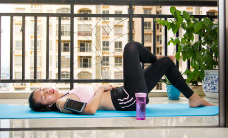 Girl relaxing on a yoga mat at home. Workout break