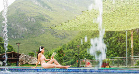 Girl in bikini reading a book by the swimming poolの写真素材