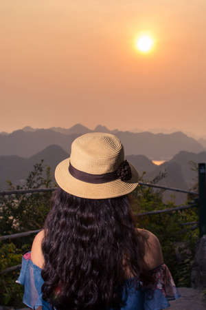Girl enjoying sunset view from Cannon fort viewpoint in Cat ba, Vietnamの写真素材