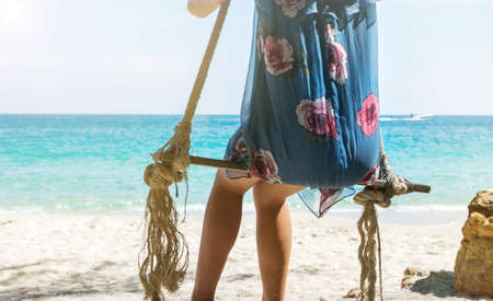 Girl sitting on a wooden swing on the beach. Summer holiday goalsの写真素材