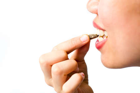 Girl eating sunflower seeds isolated on white