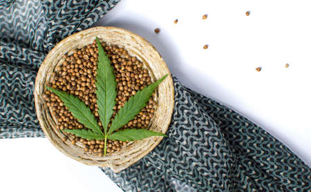 Cannabis seeds in a bowl with dark  fabric on whiteの写真素材
