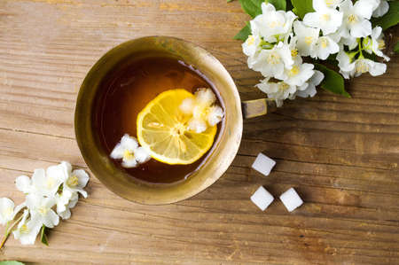 Jasmine tea with lemon in a cup surrounded by flowersの写真素材