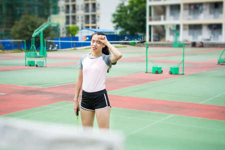 Badminton player wiping sweat on the outdoors courtの写真素材