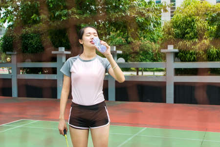 Badminton player wiping sweat on the outdoors courtの写真素材