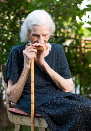 Cheerful senior woman sitting with a walking caneの写真素材