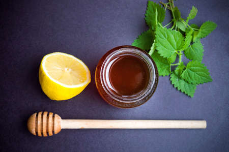 Honey jar with stinging nettle leaves and lemon