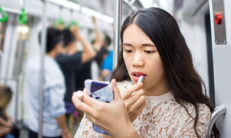 Asian girl fixing make up on subway rideの写真素材