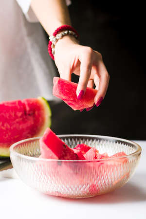 Woman taking watermelon slice from a glass bowlの写真素材